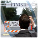 Business man scratching head as he sees a road closed sign right in front of the finish line.