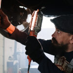 Mechanic works underneath a car.