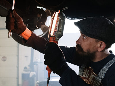 Mechanic works underneath a car.