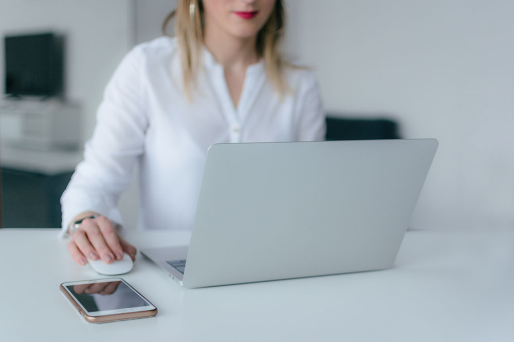 Young woman sitting at her desk and working on her laptop.