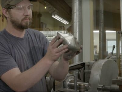 A man holding a part in a manufacturing facility.