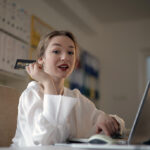 Woman holding credit card while using a laptop.