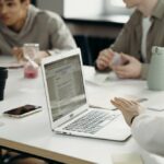 Three business people sitting at conference table with laptop having a meeting.