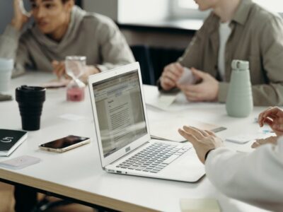Three business people sitting at conference table with laptop having a meeting.