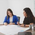 Two woman reviewing business papers at desk.