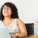 Two women laughing as they work on laptop.