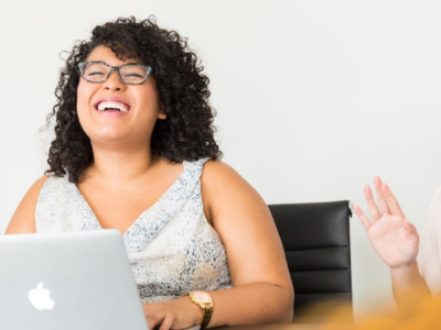Two women laughing as they work on laptop.