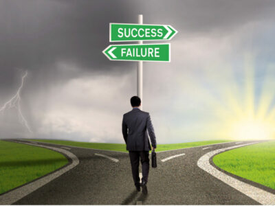Business man walking up to a fork in the road with road signs saying, "Success and Failure."