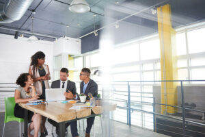 Two men and two woman looking at a laptop during a business meeting.