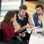 Two business men and one business woman in a wheelchair reviewing notes.