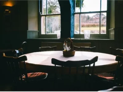 Round dining room table that seats seven with window in the background of a darkened room.