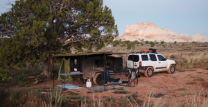 Campsite with Hiker trailer and white SUV parked in a desert landscape.