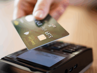 Image of a credit card being read by a scanner with Nuvei processing the payment.